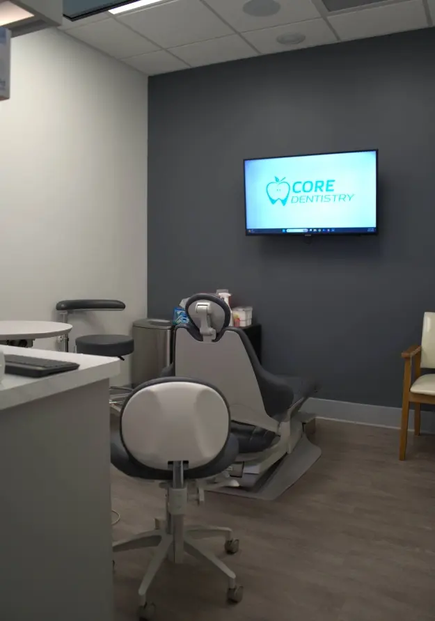 Core Dentistry treatment room with dental chair and monitor displaying practice logo.