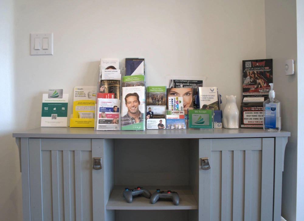 Patient amenities station with brochures, hand sanitizer, and video game controllers in the Core Dentistry waiting room
