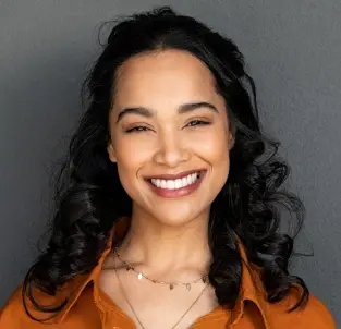 Smiling woman with healthy teeth wearing an orange shirt, representing successful dental care.